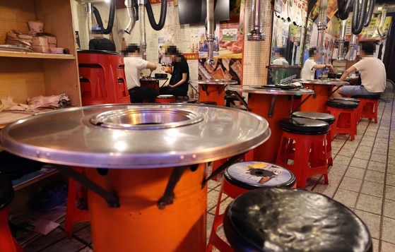 Only two customers sit on a table at a restaurant in central Seoul on July 12, the same day in which a heighten social distancing regulation that only allows two people to gather was enacted. [YONHAP] 