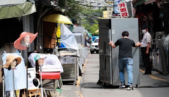 A refrigerator is moved into a second-hand store in Hwanghak-dong, central Seoul, on Tuesday. Sales of second-hand appliances have increased as many small shops are being run out of business as the Covid-19 pandemic hits sales. The government has released financial aid packages to help small shop owners, but many say its not enough. [YONHAP] 