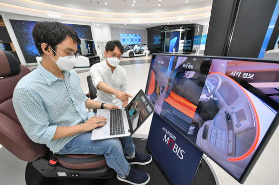 Researchers at Hyundai Mobis try out the M.Brain technology which detects brainwave and warns the driver. [HYUNDAI MOBIS]