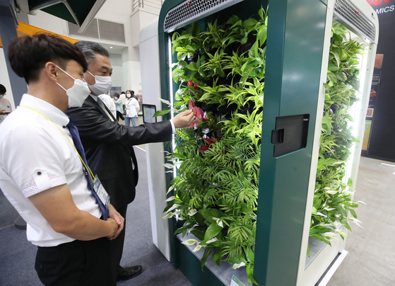 A visitor takes a look at plant-based air purifier Airim developed by Biocraft at the Korea International Cooling Industry Expo held in Daegu on Wednesday. The expo, which runs through July 23, is dedicated to displaying various products that can counter climate change and improve air quality. [YONHAP]