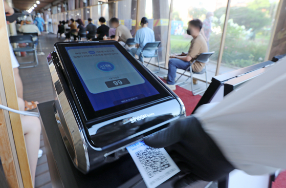 People take numbered tickets to wait their turns for Covid-19 tests in Songpa District, southern Seoul, on Thursday. Songpa District began a queue system at Covid-19 testing sites from Thursday so people can wait in a separate air-conditioned waiting area to get out of the heat. [YONHAP]