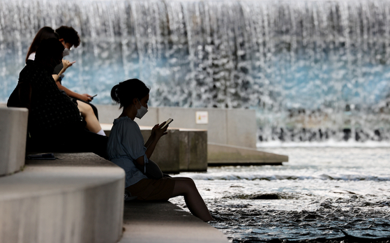 People cool themselves off under a bridge at the Cheonggyecheon, a restored stream that runs through in Jongno District, central Seoul, on Tuesday, as the scorching heat prevails. [YONHAP]