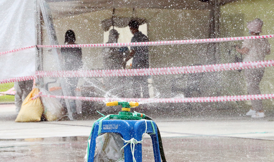 Water is sprinkled to beat the heat at a temporary screening clinic for coronavirus tests in Daegu on Thursday, as a heat wave continues to grip Korea. [YONHAP]