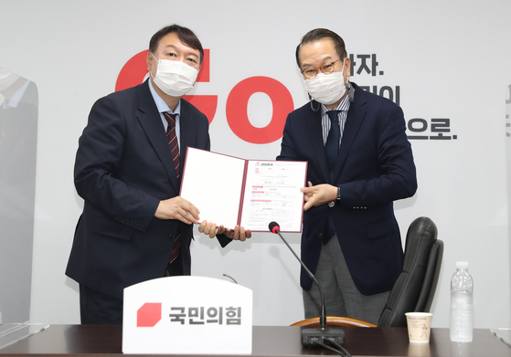 Former Prosecutor General Yoon Seok-youl, left, a conservative presidential candidate, submits his application to join the main opposition People Power Party (PPP) to Rep. Kwon Young-se, chief of the party’s external relations committee, at the PPP headquarters in Yeouido, western Seoul, Friday. [NEWS1] 