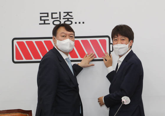 Lee Jun-seok, right, chairman of the main opposition People Power Party (PPP), poses next to the image of a full-charged battery, symbolizing all presidential contenders joining the race, along with Yoon Seok-youl, left, former prosecutor general and presidential front runner, after Lee had a meeting with Yoon in the National Assembly on Monday. Yoon announced he will join the PPP on Friday while Lee was out of Seoul. [YONHAP]