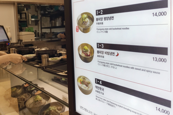 A menu shows naengmyeon, noodles in cold meat broth, priced at 13,000 won ($11) and 14,000 won at a store in Myeongdong, central Seoul, on Monday. According to the Korea Consumer Agency, naengmyeon was priced at an average 9,577 won at restaurants in July, up 6.41 percent on year. [YONHAP]
