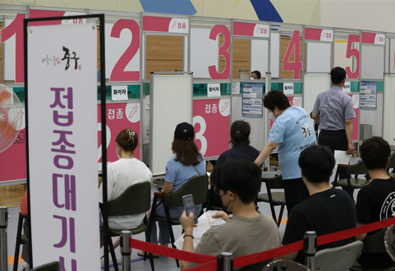 People wait for inoculations at a Covid-19 vaccination center in Jung District, central Seoul, on Tuesday afternoon. As of Monday midnight, 51.2 percent of the country's population had received one vaccine shot. [NEWS1]