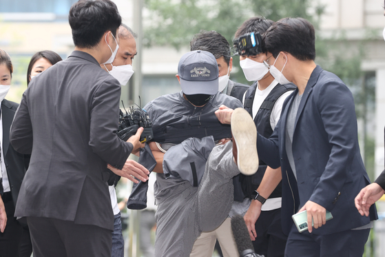 A murder suspect on Tuesday kicks reporters on his way to a warrant hearing at the Seoul Eastern District Court. [YONHAP]