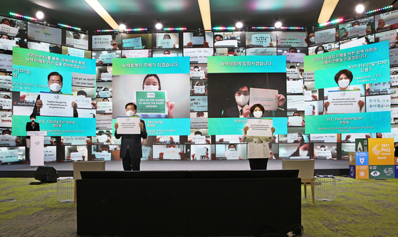 Korean Foreign Minister Chung Eui-young, left, and Environment Minister Han Jeoung-ae hold up messages on climate change, joined by hundreds of participants from around the world, at the opening ceremony of the Green Future Week at the Dongdaemun Design Plaza in central Seoul Monday, ahead of the P4G Seoul Summit. [PARK SANG-MOON]