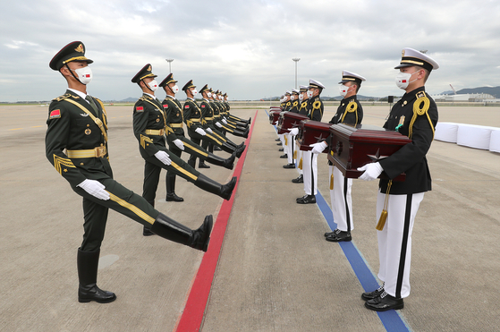 South Korean and Chinese soldiers take part in a handover ceremony at Incheon International Airport Thursday to repatriate the remains of 109 Chinese troops killed during the 1950-53 Korean War. The remains were excavated from battle sites from the war between 2019 and 2020, including at the Arrowhead Ridge in the demilitarized zone. [DEFENSE MINISTRY]