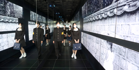 Models dressed in 1960s-style school uniforms walk past black-and-white photo images displayed at Lotte Tower’s observatory Seoul Sky in Jamsil, Seoul, on Tuesday. Lotte World is exhibiting works by late photographer Han Young-so of 1960s Seoul. Han was known as one of the leading photographers in fashion and advertisement. [YONHAP]