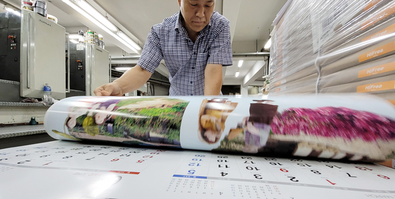 An employee checks next year’s calendar at a printing press in Jung District in Seoul on Tuesday. Korea has a busy year in 2022 starting with the presidential election on March 9 and local elections to be held on June 1. While traditional calendars have seen a sharp drop in sales due to smartphones, they still remain popular for nostalgic and sentimental reasons. [YONHAP]