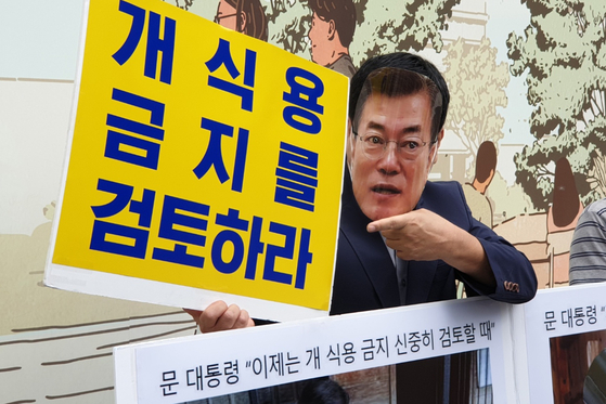 Local animal rights activists hold a rally at the Gwanghwamun Square in central Seoul on Tuesday to call for the banning of dog meat consumption in the country. One activist, wearing a mask of President Moon Jae-in, is holding a sign that reads, "Review banning dog meat consumption." [YONHAP]