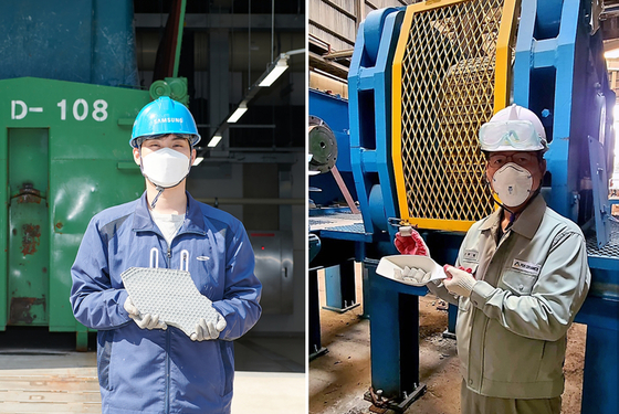 A Samsung Electronics employee, left, and a Pos Ceramics employee pose for a photo holding wastewater sludge and the fluorite alternative product that was made with it. [SAMSUNG ELECTRONICS] 