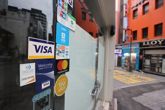 Credit card logo on a store that has been closed in Myeong-dong, Seoul on Monday. The government said a cash-back program whose goal is to help small stores that have been affected by the social distancing regulation will start Oct. 1. [YONHAP] 