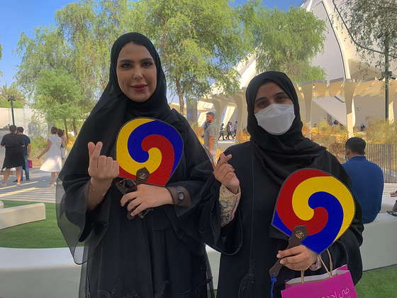 Visitors to the Korea Pavilion, Norah Awad from Saudi Arabia, left, and Wasmeya Alrashdi from Abu Dhabi, pose for a photo holding fans from the pavilion. They told the Korea JoongAng Daily that they especially liked the Korean food. [SARAH CHEA]