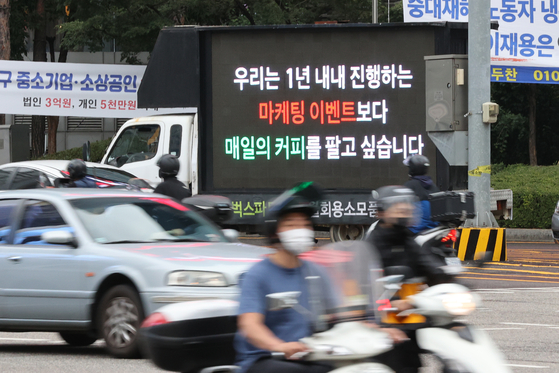  A truck with a sign that reads “We want to make coffee everyday, not run marketing events throughout the entire year” is parked on a street near Gangnam station in southern Seoul on Thursday. Starbucks baristas paid for the mobile signs to drive around Seoul to protest the company’s promotional events that have left them overworked and understaffed. The protest follows the Sept. 28 free reusable plastic cup event, which left some Starbucks coffee shops with a backlog of several hours after orders poured in. [YONHAP]