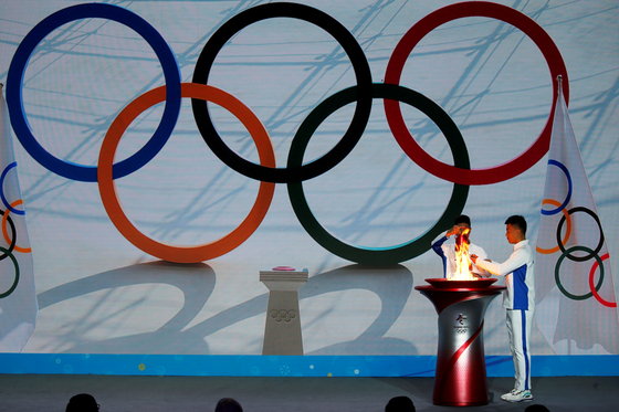 Participants transfer the Olympic flame from a cauldron at the ceremony to welcome the flame for the Beijing 2022 Winter Olympics in Beijing on Oct. 20. [REUTERS/YONHAP]