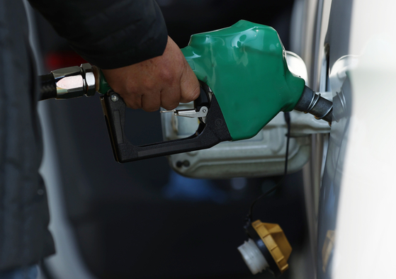 A driver pumps fuel at a gas station in Seoul on Tuesday. Gas price hikes have led to other price increases through the economy. [YONHAP] 