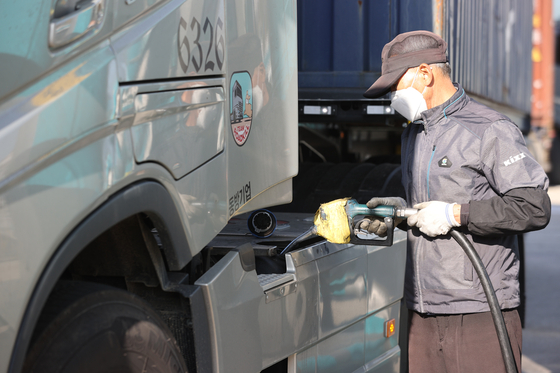 A gas station employee in Euiwang, Gyeonggi, on Wednesday fills up DEF on a cargo truck. [YONHAP] 