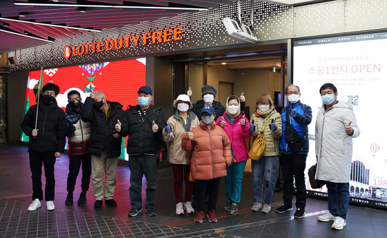 A group of tourists from Singapore pose in front of the Lotte Duty Free store in central Seoul on Monday. They were the first group of foreign tourists there in almost two years after overseas travel was limited due to the pandemic. Korea and Singapore signed a travel bubble agreement which became effective on Nov. 15. [LOTTE DUTY FREE]