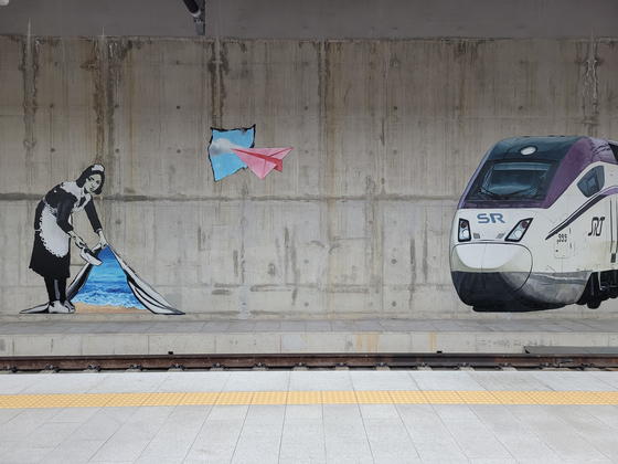 A public mural drawn on the platform of Suseo's SRT station that is causing controversy, with some calling it a cheap imitation of Banksy's “Sweep It Under The Carpet.” [MOON SO-YOUNG]