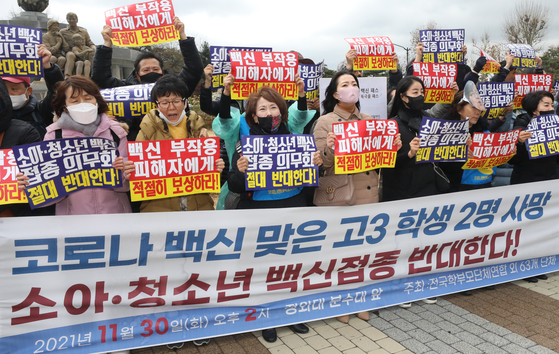 Parents of students across the nation stage a protest near the Blue House on Tuesday in opposition of the mandatory inoculation of underage kids, citing the deaths of two high school seniors after getting vaccinated. [NEWS1]