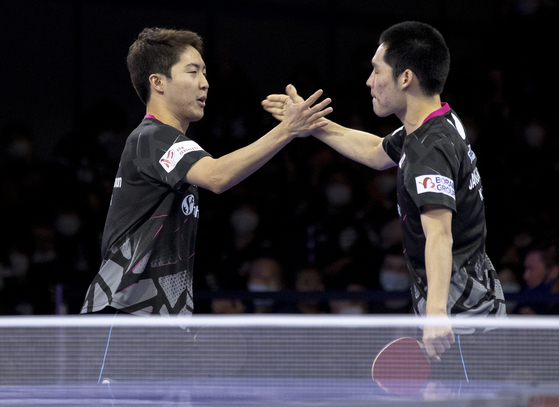 Lim Jong-hoon, left, and Jang Woo-jin celebrate during the men's doubles semifinal match against Japan's Togami Shunsuke and Uda Yukiya at the 2021 World Table Tennis Championships Finals in Houston, Texas, on Sunday. [XINHUA/YONHAP]
