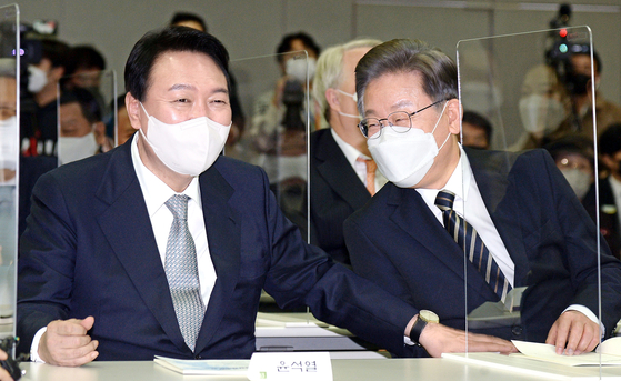 Yoon Suk-yeol, left, presidential candidate of the opposition People Power Party (PPP), converses with Lee Jae-myung, presidential candidate of the ruling Democratic Party (DP), in the Kim Dae-jung Library at Yonsei University in western Seoul on Thursday at the commemoration of the 21st anniversary of former President Kim Dae-jung winning the Nobel Peace Prize. [JOINT PRESS CORPS]