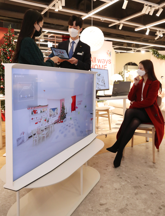 A Hanssem employee explains a home interior plan for a customer using an example generated on the metaverse at Hanssem Design Park in Mapo District, western Seoul, on Thursday. [YONHAP]