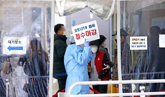 A staffer at a virus screening center in Mapo District, western Seoul, holds a sign saying applications for Covid-19 tests for the morning were closed on Thursday. [YONHAP]