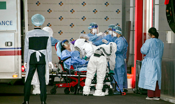 Medical workers wearing protective gear move a coronavirus patient from an ambulance at Seoul Medical Center in Jungnang District, eastern Seoul, on Tuesday. [YONHAP]