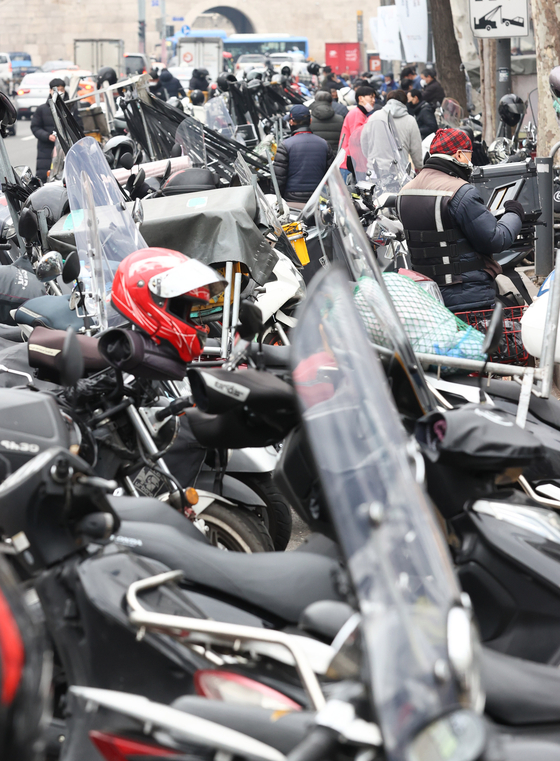  Delivery motorcycles parked at the Dongdaemun Shopping Complex, eastern Seoul, on Tuesday. According to the Ministry of Employment and Labor on Tuesday, quick-delivery-service bikers and designated drivers will be allowed to subscribe for employment insurance starting 2022. Companies running the ordering apps will be considered employers and pay half the 1.4-percent-of-income premium, while the bikers will pay the other half. It is part of the government's policy of getting all working people under employment insurance. These workers have been denied employment insurance as they are considered private contractors. [YONHAP]