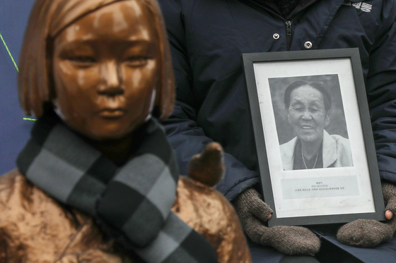 Students and members of civic groups supporting the victims of Japanese wartime sexual slavery hold up a photo of a late victim as they protest near the Japanese Embassy in Seoul on Wednesday, which marked the 30th anniversary of the weekly rallies. [NEWS1]
