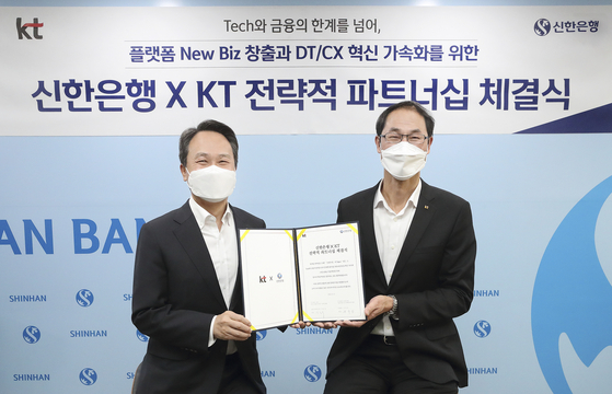 Jin Ok-dong, Shinhan Bank CEO, left, and Park Jong-ook, President of KT, at a strategic partnership ceremony held at Shinhan Bank's main branch in central Seoul on Monday. [KT] 