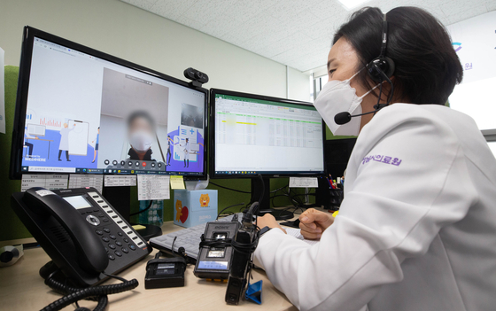 A medical worker talks to a coronavirus-infected patient via video link at Seongnam Citizens Medical Center in Seongnam, Gyeonggi, on Friday. The patient is being treated at home with Paxlovid, Covid-19 treatment pills developed by U.S. pharmaceutical giant Pfizer. [YONHAP]