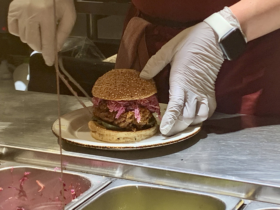 A chef at Le Freak makes a Nashville Hot Chicken sandwich in the restaurant's open kitchen. [LEE JIAN]