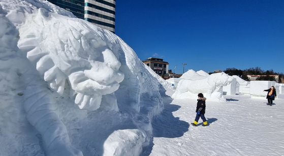 Tourists take a look at snow sculptures on display in Pyeongchang County, Gangwon, on Sunday, after the Daegwallyeong Snow Festival was canceled as Omicron variant infections surged.  [YONHAP]