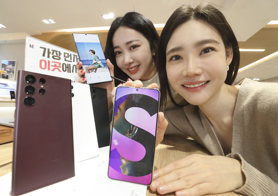 Staffers at KT hold up the new Galaxy S22 smartphones. Telecom companies are offering a bundle of benefits to people who place their orders from Feb. 14 to 21. [KT]