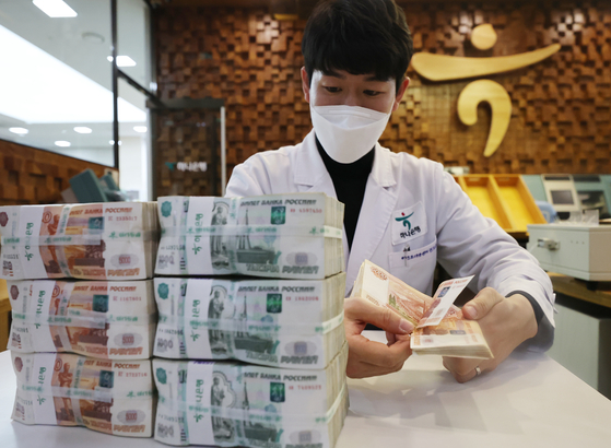 An employee counts ruble bills at a Hana Bank branch in Jung District, central Seoul, Monday. The Russian ruble plunged some 28 percent against the dollar, trading at a record low of 117.817 to the dollar on Monday, due to the latest financial sanctions following Russia's invasion of Ukraine. [YONHAP] 