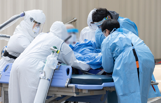 Paramedics and medical staff transfer a Covid-19 patient at Seoul Medical Center in Jungnang District, eastern Seoul, on Tuesday. [NEWS1] 