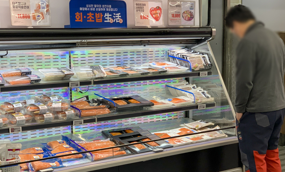 A customer looks at salmon displayed at a supermarket in Seoul on Sunday. The price of salmon fillets at retail markets increased between 15 to 26 percent last week compared to the beginning of the month, according to industry insiders. The price of Norwegian salmon has been rising due to the Russian invasion of Ukraine, as the Norwegian fish products used to be imported through Russia but now must be shipped on a longer route, topped with rising oil prices around the world. [YONHAP]