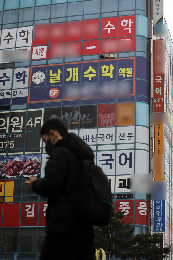 A pedestrian passes by a building filled with hagwon, or cram schools, in Seoul on Sunday. Last year, 23.4 trillion won ($18.9 billion) was spent on private tutoring in Korea, the highest amount ever and 21.5 percent higher than 2020, according to a report by the Ministry of Education and Statistics Korea. The monthly average amount spent on private tutoring for a student in Korea was 367,000 won in 2021. [NEWS1]