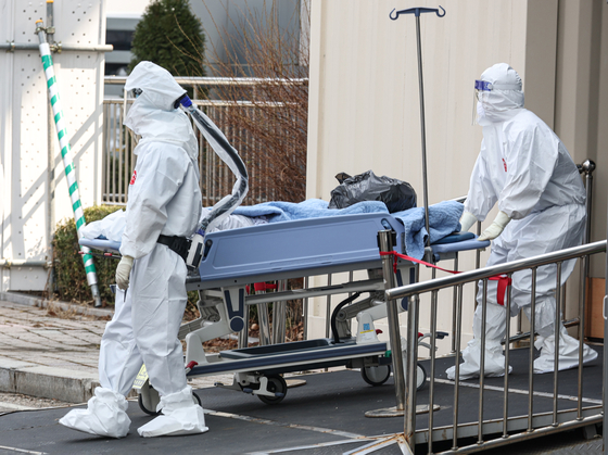 Medical workers in protective gear transfer a Covid-19 patient at Seoul Medical Center in Jungnang District, eastern Seoul, on Tuesday. [YONHAP]