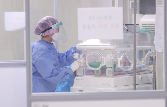 A nurse tends to a baby born to a Covid-positive mother. [YONHAP]