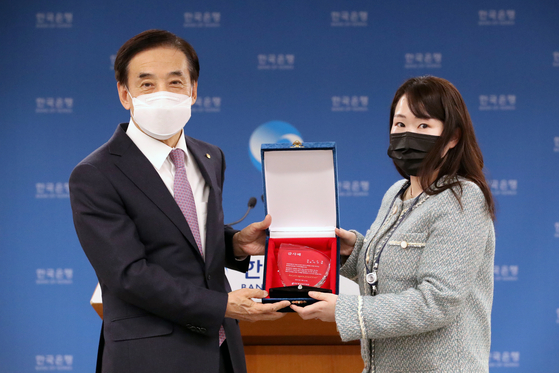 Bank of Korea Governor Lee Ju-yeol, left, receives a plaque of appreciation at a farewell press conference in central Seoul on Thursday. Lee finishes his term on March 31 after serving eight years. [BOK]