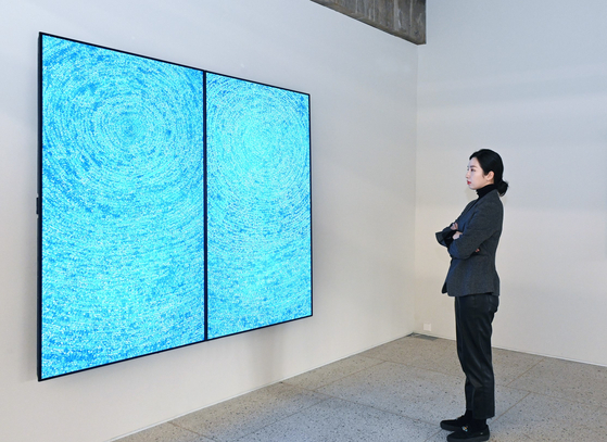 A model looks at a digital version of the iconic painting "05-IV-71 #200 (Universe)" by Korean modern art master Kim Whanki (1913-1974) on an LG OLED display at Gana Art Bogwang in Yongsan, central Seoul. [LG ELECTRONICS] 