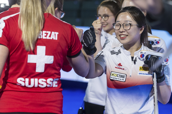 Korean lead Kim Seon-yeong, right, fist bumps Switzerland's Melanie Barbezat as the two teams are announced prior to the gold medal game during the World Women's Curling Championship in Prince George, British Columbia, on Sunday. [AP/YONHAP]
