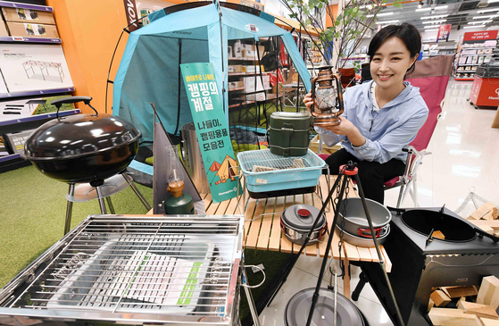 A model poses with camping gear, including tents, at Homeplus. The retailer is holding a special event for Homeplus membership customers by offering up to 40 percent off on camping gear, including foldable chairs and tables. With the weather becoming warmer and social distancing regulations easing, retailers are heavily marketing camping products. [HOMEPLUS]