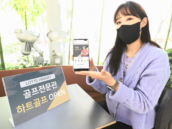 Model poses with Lotte Hi-Mart online golf store app.[LOTTE HI-MART] 